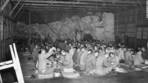 circa 1951: North Korean POWs make baskets as they sit in rows on the floor of a storage barn at Taegu National Prison in Korea during the Korean War. (Photo by Hulton Archive/Getty Images)